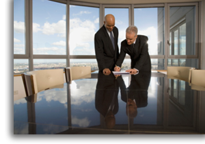 Businessmen looking at and signing documents in conference room.