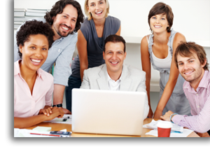 A group of coworkers sitting around a computer and desk.