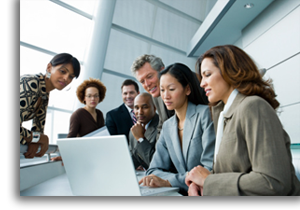 A group of coworkers all viewing the same laptop screen.